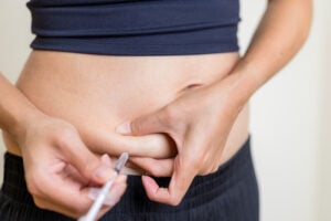 A woman is injecting semaglutide in Prosper, TX, into her abdomen with a syringe.